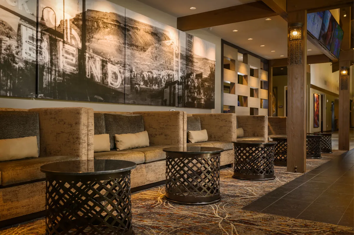 This interior scene features a comfortable sitting area with plush armchairs, a coffee table, and large wall art depicting a landscape. The inviting arrangement suggests a spot for relaxing, reading, or sipping coffee—activities mentioned in the section's narrative. Soft lighting and cozy décor add to the suite’s welcoming atmosphere.